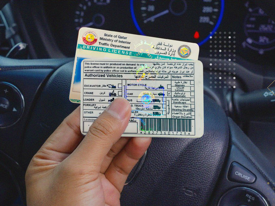 Qatar driving license held loosely in hand inside a car